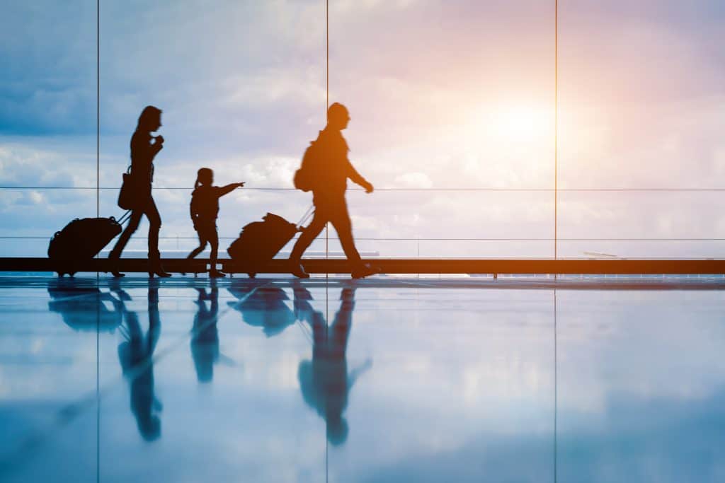 Family at airport travelling with young child and luggage walking