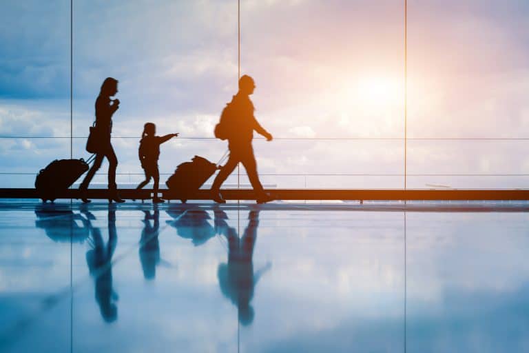 Family at airport travelling with young child and luggage walking