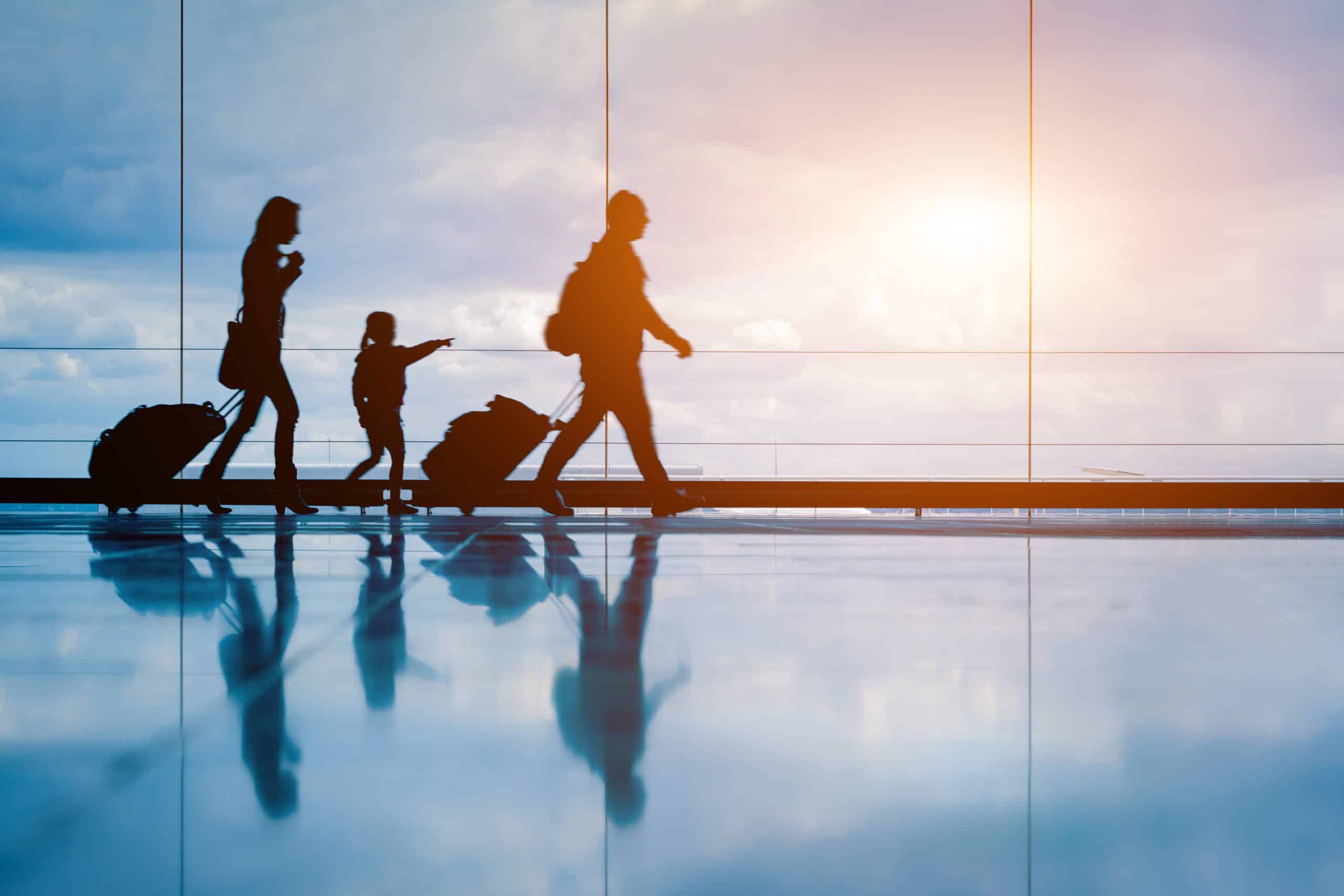 Family at airport travelling with young child and luggage walking